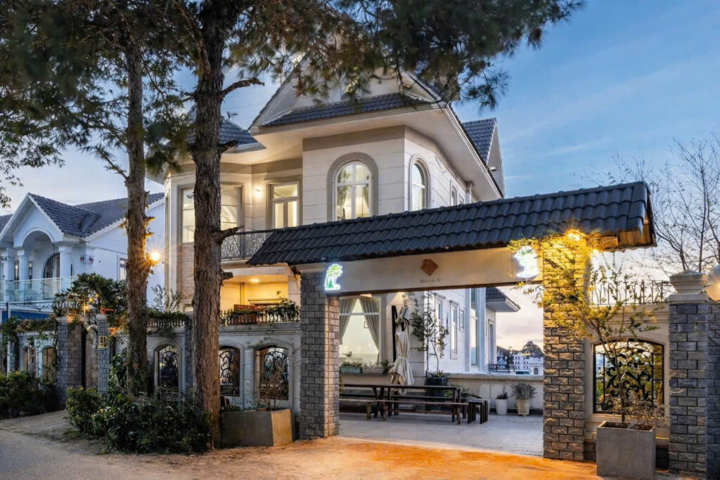 # 🌸 Villa Đà Lạt View Nhà Lồng – 8 Phòng Ngủ, Xe 50 Chỗ Vào Tận Nơi Nếu bạn đang tìm một **villa Đà Lạt cho nhóm đông**, có **view nhà lồng lung linh về đêm, đường lớn dễ di chuyển và xe 50 chỗ có thể vào tận nơi**, căn villa tại **Trịnh Hoài Đức, Phường 11, Đà Lạt** là lựa chọn phù hợp cho gia đình, nhóm bạn, đoàn du lịch hoặc team building. Villa sở hữu **8 phòng ngủ, 8 WC riêng**, sức chứa tiêu chuẩn **12-18 khách và tối đa 24 khách khi sử dụng thêm nệm phụ**. Không gian sinh hoạt chung gồm phòng khách, bếp, sân vườn BBQ và sân thượng view thung lũng đèn, đáp ứng tốt nhu cầu nghỉ dưỡng và tổ chức các hoạt động tập thể. ## 🌃 Villa Đà Lạt view nhà lồng – Ngắm thung lũng đèn về đêm Một trong những điểm hấp dẫn nhất của căn villa là **view nhà lồng Đà Lạt về đêm**. Từ sân thượng, du khách có thể ngắm những khu nhà lồng lên đèn tạo nên khung cảnh đặc trưng của Đà Lạt. Đây cũng là khu vực thích hợp để: * Ngắm cảnh và thư giãn. * Uống cafe, trò chuyện cùng bạn bè. * Chụp ảnh check-in. * Tận hưởng không khí Đà Lạt về đêm. Nếu bạn yêu thích khung cảnh **thung lũng đèn Đà Lạt**, đây là một điểm cộng đáng chú ý của căn villa. ## 🛏️ Villa 8 phòng ngủ – Sức chứa tối đa 24 khách Villa được bố trí **8 phòng ngủ**, phù hợp với những nhóm khách đông muốn có không gian nghỉ ngơi riêng cho từng gia đình hoặc nhóm nhỏ. ### Cơ cấu phòng: * **7 phòng đơn**. * **1 phòng đôi**. * **8 WC riêng**. * Sức chứa tiêu chuẩn: **12-18 khách**. * Sức chứa tối đa: **24 khách khi sử dụng thêm nệm phụ**. Các phòng có không gian rộng rãi, sạch sẽ và được trang bị WC riêng, mang lại sự thuận tiện cho nhóm đông người trong suốt thời gian lưu trú. ## 🍖 Sân BBQ rộng – Không gian sinh hoạt ngoài trời Villa có **sân rộng dành cho BBQ ngoài trời**, rất phù hợp để các nhóm tổ chức những bữa tiệc nhỏ hoặc hoạt động tập thể. Bạn có thể cùng gia đình và bạn bè chuẩn bị đồ ăn, nướng BBQ và thưởng thức ngay tại villa mà không cần di chuyển ra ngoài. Không gian sân cũng có thể tận dụng để tổ chức các hoạt động chung cho nhóm. ## 🛋️ Phòng khách & bếp đầy đủ tiện nghi Khu vực sinh hoạt chung được thiết kế để phục vụ nhu cầu ăn uống, nghỉ ngơi và trò chuyện của cả nhóm. Villa trang bị: * 📺 Phòng khách có TV lớn. * 🍳 Bếp đầy đủ tiện nghi. * 🧊 Tủ lạnh. * 🔥 Lò vi sóng. * 🍽️ Các dụng cụ cần thiết phục vụ sinh hoạt. * 🔑 Giao chìa khóa nguyên căn. Việc thuê nguyên căn giúp nhóm khách có không gian sinh hoạt riêng, thuận tiện cho những chuyến đi gia đình hoặc nhóm bạn. ## 🚐 Đường lớn – Xe 4 đến 50 chỗ vào tận nơi Một ưu điểm nổi bật của căn villa là **đường lớn, rộng rãi và thuận tiện di chuyển**. Villa có sân đậu xe phù hợp cho nhiều loại phương tiện, từ xe nhỏ đến xe du lịch: * Xe 4 chỗ. * Xe 7 chỗ. * Xe du lịch. * **Xe 50 chỗ có thể vào tận nơi.** Đây là lợi thế lớn đối với các đoàn đông người, tour du lịch hoặc nhóm tổ chức team building tại Đà Lạt. ## 📍 Vị trí Villa tại Trịnh Hoài Đức, Phường 11 Villa tọa lạc tại: **Trịnh Hoài Đức, Phường 11, Đà Lạt.** Từ villa, du khách có thể thuận tiện kết hợp nghỉ dưỡng với lịch trình khám phá thành phố, ăn uống và thưởng thức cafe Đà Lạt. Khu vực xung quanh có các điểm tham quan, quán ăn và quán cafe, giúp việc lên lịch trình cho nhóm dễ dàng hơn. ## 👨‍👩‍👧‍👦 Villa phù hợp cho gia đình, nhóm bạn và đoàn đông Với sức chứa tiêu chuẩn **12-18 khách và tối đa 24 khách**, căn villa phù hợp với: * Gia đình nhiều thành viên. * Nhóm bạn đi Đà Lạt. * Nhóm từ 12-18 người. * Đoàn tối đa 24 khách. * Team building. * Đoàn du lịch. * Nhóm muốn tổ chức BBQ ngoài trời. * Những nhóm cần villa có sân đậu xe rộng. ## ⭐ Những điểm nổi bật của Villa **✔ 8 phòng ngủ – 8 WC** Phù hợp cho nhóm đông cần không gian nghỉ ngơi riêng. **✔ View nhà lồng Đà Lạt** Đặc biệt đẹp khi thành phố lên đèn vào buổi tối. **✔ Sân thượng view thung lũng đèn** Không gian lý tưởng để ngắm cảnh và check-in. **✔ Sân BBQ rộng** Thích hợp tổ chức tiệc BBQ và sinh hoạt nhóm. **✔ Xe 50 chỗ vào tận nơi** Thuận tiện cho đoàn du lịch và nhóm đông. **✔ Giao chìa khóa nguyên căn** Không gian sử dụng riêng cho đoàn khách. **✔ Cách bố trí phù hợp nhóm đông** 7 phòng đơn + 1 phòng đôi, tiêu chuẩn 12-18 khách, tối đa 24 khách với nệm phụ. ## 📋 Thông tin nhanh | Hạng mục | Thông tin | | ------------------- | --------------------------------- | | Loại hình | Villa nguyên căn Đà Lạt | | Số phòng ngủ | 8 phòng | | Cơ cấu phòng | 7 phòng đơn + 1 phòng đôi | | Số WC | 8 WC | | Sức chứa tiêu chuẩn | 12-18 khách | | Tối đa | 24 khách + nệm phụ | | View | Nhà lồng, thung lũng đèn | | Sân thượng | Có | | Sân BBQ | Có | | Phòng khách | TV lớn | | Bếp | Có | | Tủ lạnh | Có | | Lò vi sóng | Có | | Chìa khóa | Giao nguyên căn | | Đậu xe | Xe 4-50 chỗ | | Địa chỉ | Trịnh Hoài Đức, Phường 11, Đà Lạt | # 🏡 Villa Đà Lạt View Nhà Lồng – Lựa Chọn Cho Nhóm 12-24 Khách Sở hữu **8 phòng ngủ, 8 WC, view nhà lồng và thung lũng đèn, sân thượng, sân BBQ rộng, bếp đầy đủ tiện nghi cùng khả năng đón xe 50 chỗ**, căn villa tại Trịnh Hoài Đức là lựa chọn phù hợp cho các gia đình, nhóm bạn và đoàn đông khi đến Đà Lạt. Nếu bạn đang tìm **villa Đà Lạt 8 phòng ngủ**, cần không gian rộng để sinh hoạt chung, tổ chức BBQ và thuận tiện cho xe du lịch lớn, căn villa này là một lựa chọn đáng tham khảo. --- ## 🔎 SEO ON-PAGE **SEO Title:** Villa Đà Lạt View Nhà Lồng – 8 Phòng Ngủ, 12-24 Khách **Meta Description:** Villa Đà Lạt view nhà lồng tại Trịnh Hoài Đức, Phường 11. 8 phòng ngủ, 8 WC, sức chứa 12-18 khách, tối đa 24 khách, sân BBQ, sân thượng view thung lũng đèn, xe 50 chỗ vào tận nơi. **Focus Keyword:** Villa Đà Lạt View Nhà Lồng **Từ khóa SEO:** Villa Đà Lạt view nhà lồng, Villa Đà Lạt 8 phòng ngủ, Villa Đà Lạt 12-24 khách, Villa Đà Lạt cho nhóm đông, Villa Đà Lạt Phường 11, Villa Đà Lạt Trịnh Hoài Đức, Villa Đà Lạt view thung lũng đèn, Villa Đà Lạt có sân BBQ, Villa Đà Lạt xe 50 chỗ, Villa nguyên căn Đà Lạt, Villa Đà Lạt cho đoàn đông, Villa Đà Lạt team building, Villa Đà Lạt view đẹp, Villa Đà Lạt gần trung tâm **Hashtag:** #VillaDaLat, #VillaDaLatViewNhaLong, #VillaDaLat8PhongNgu, #VillaDaLat12Den24Khach, #VillaDaLatViewThungLungDen, #VillaDaLatPhuong11, #VillaDaLatTrinhHoaiDuc, #VillaDaLatCoSanBBQ, #VillaDaLatXe50Cho, #VillaNguyenCanDaLat, #VillaDaLatNhomDong, #VillaDaLatTeamBuilding, #DuLichDaLat, #HomestayDaLat **Slug:** `villa-da-lat-view-nha-long-8-phong-ngu` **ALT ảnh:** villa Đà Lạt view nhà lồng, villa Đà Lạt 8 phòng ngủ, villa Đà Lạt view thung lũng đèn, sân BBQ villa Đà Lạt, villa Đà Lạt xe 50 chỗ, villa Trịnh Hoài Đức Phường 11